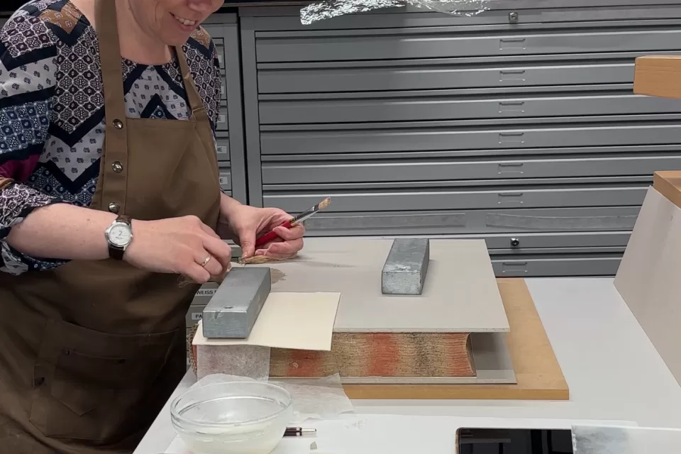 Laura bearbeitet ein Buch in der Werkstatt