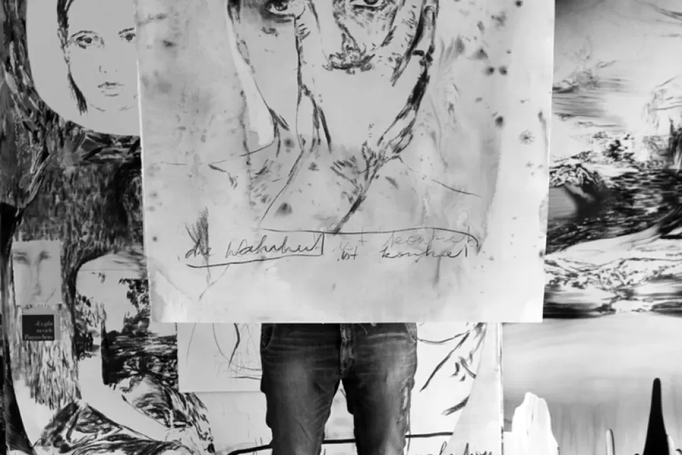 Eine Person hält eine Zeichnung vor dem Oberkörper und Kopf