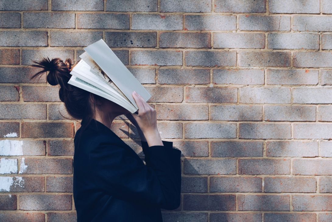 Frau mit aufgeschlagenem Buch über ihrem Gesicht